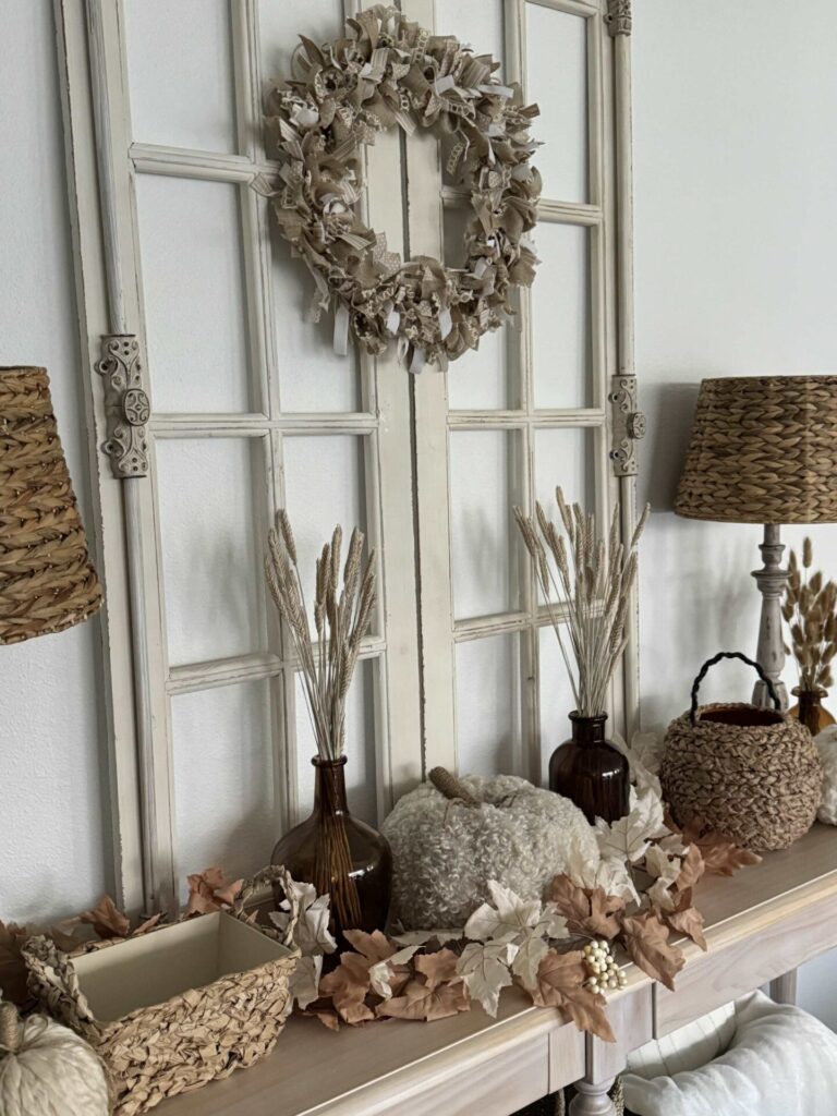 A table decorated for fall with baskets, pumpkins, and amber glass vases. 