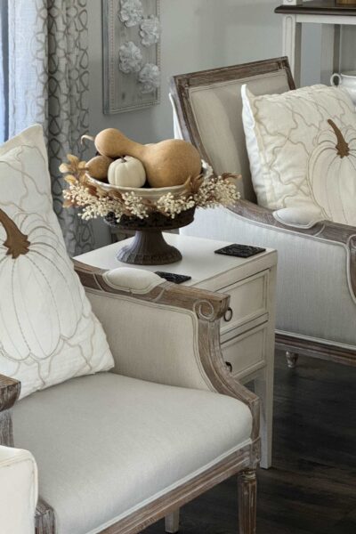 Large pumpkin pillows in two white chairs.