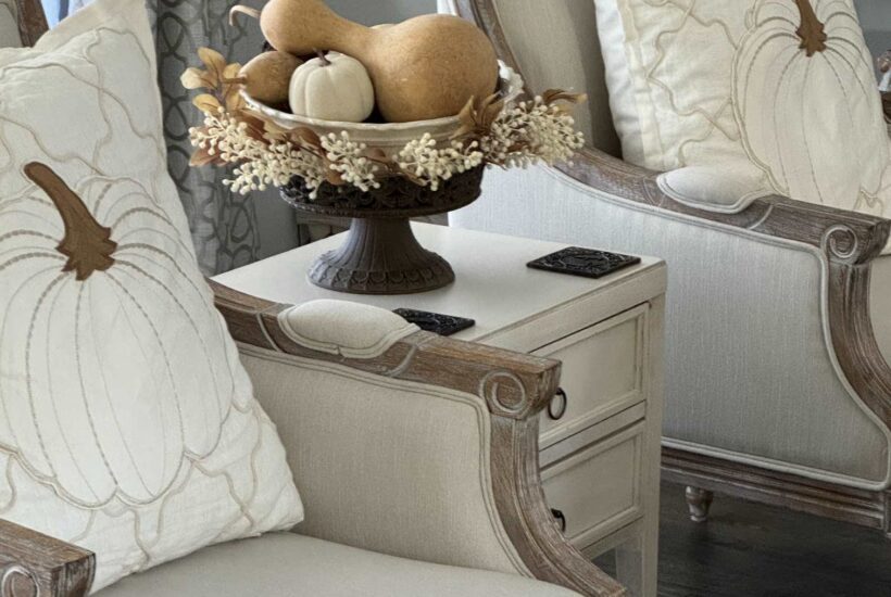 Large pumpkin pillows in two white chairs.
