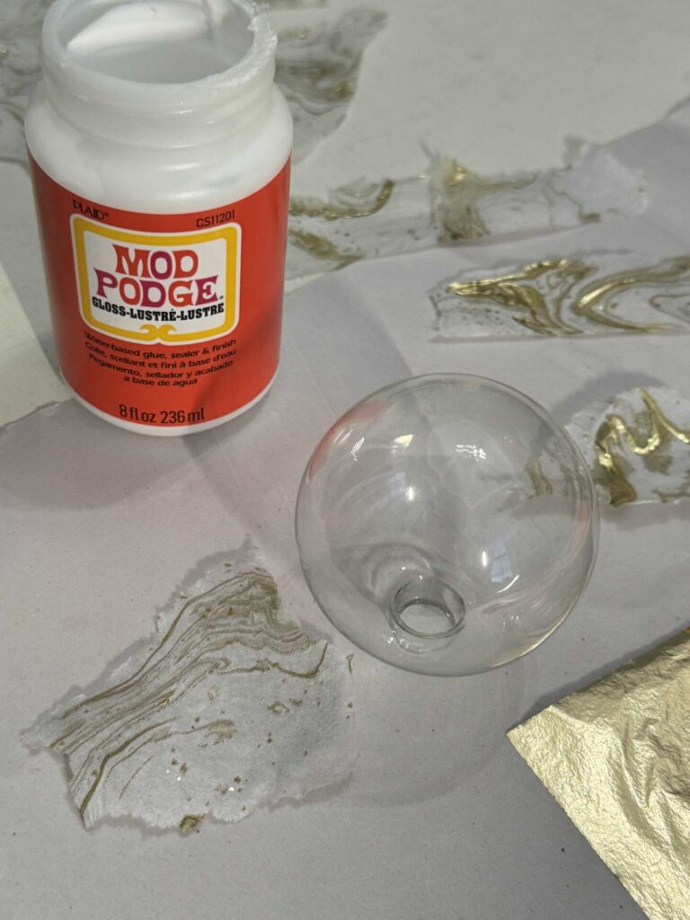 Glass ornament, torn napkins, and bottle of Mod Podge. 