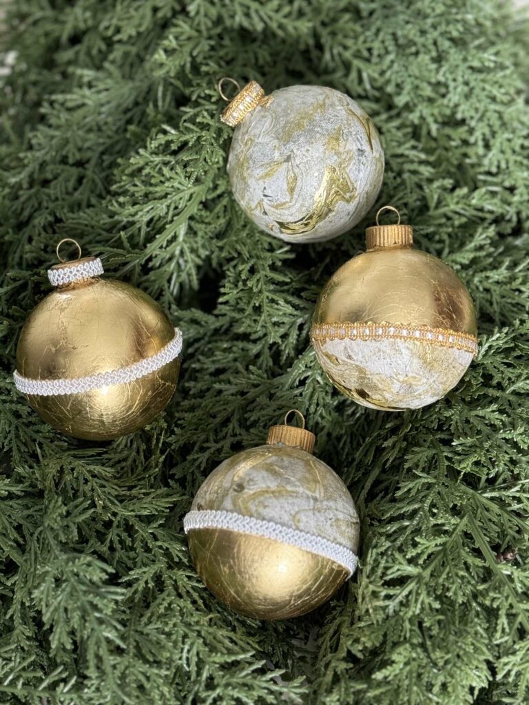 Four gold leaf and decoupage ornaments on greenery. 