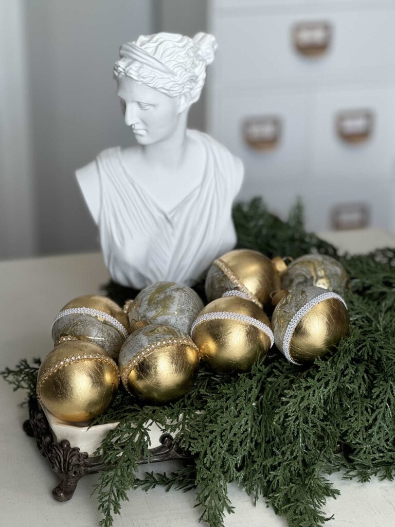 A bust statue with gold leaf ornaments displayed in front of it. 