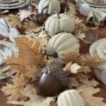 Neutral leaves, pumpkins, and acorns lining a table.