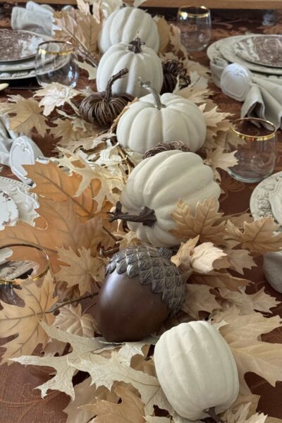 Neutral leaves, pumpkins, and acorns lining a table.