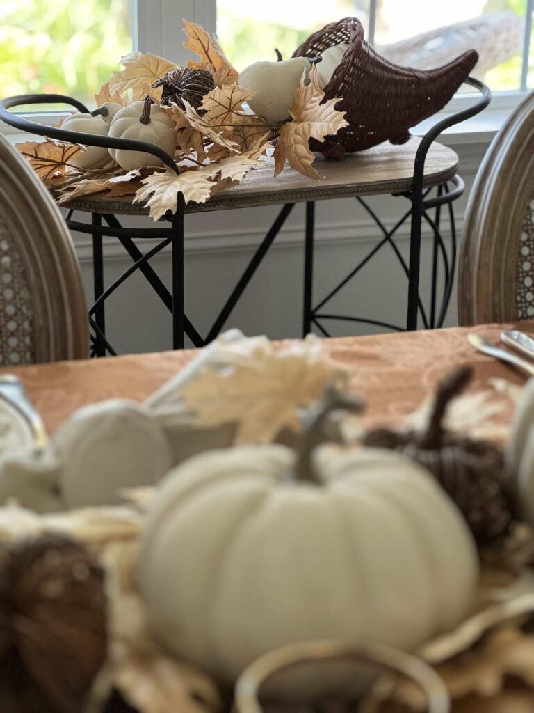 A cornucopia filled with tan leaves and white pumpkins. 