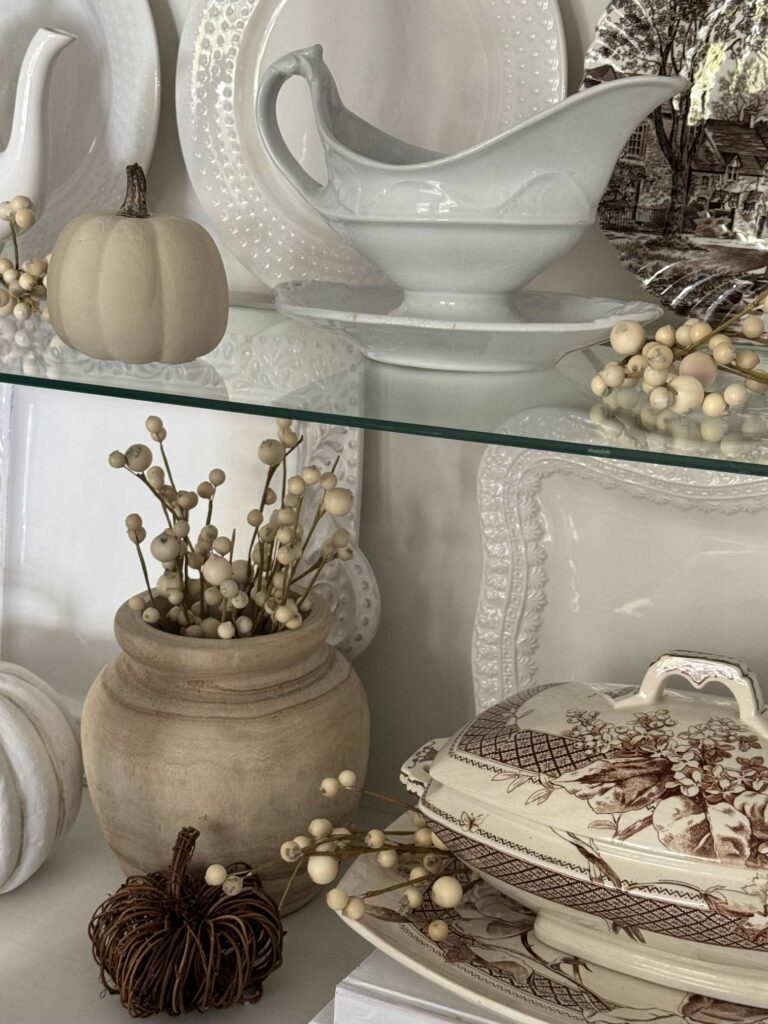 White gravy set and wooden bowl in a china cabinet. 