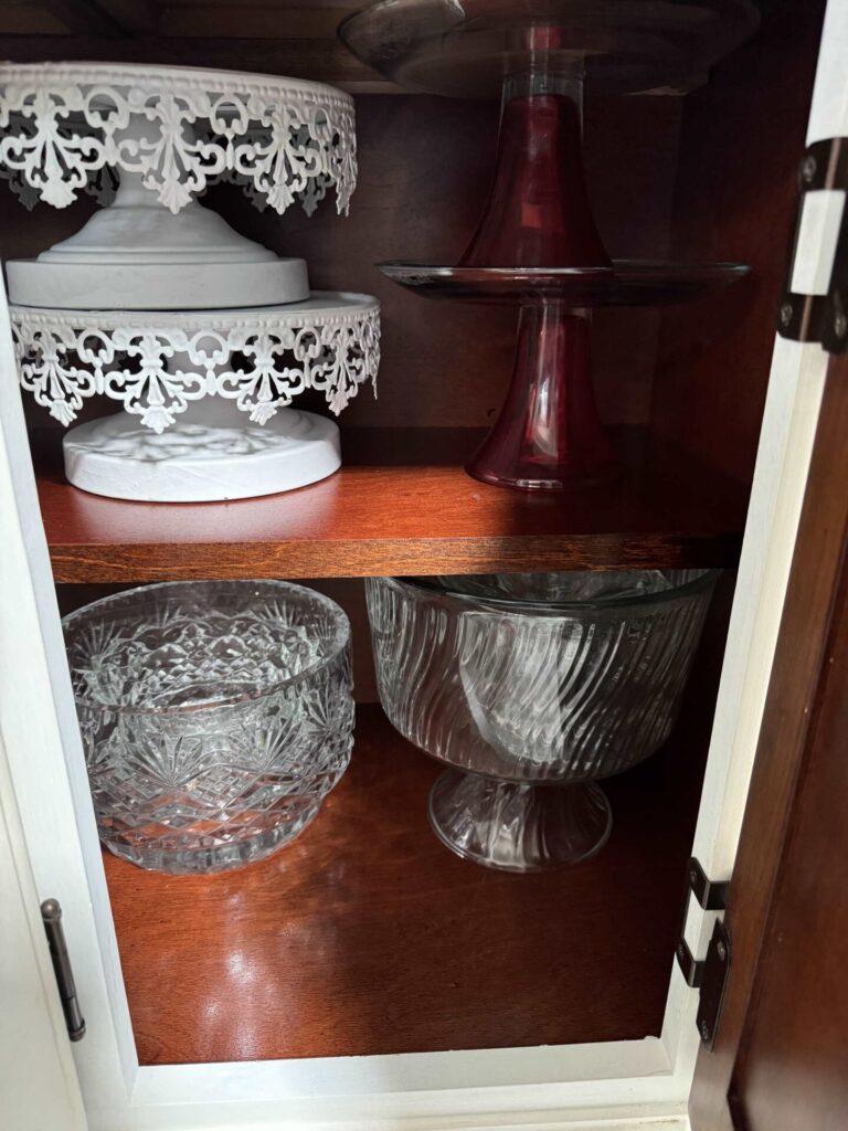 Cake stands and bowls organized in a china cabinet. 