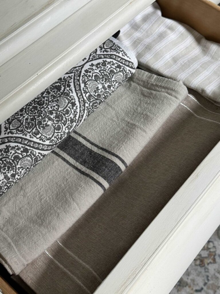 Table runners organized in a drawer of a china cabinet. 