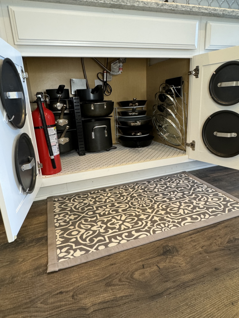 Pots, pans, and lids organized in a kitchen cabinet. 