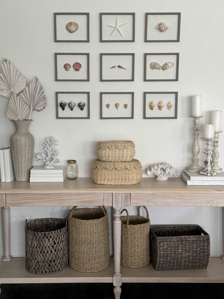 Console table decorated for summer with a gallery wall of shell pictures. 