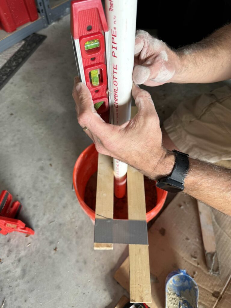 Man leveling pole in a bucket filled with cement. 