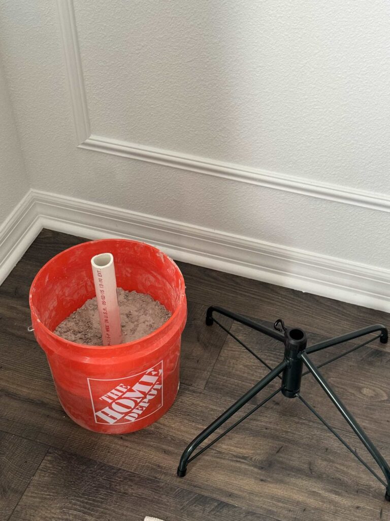 Home made tree stand with pipe and bucket next to a traditional one. 