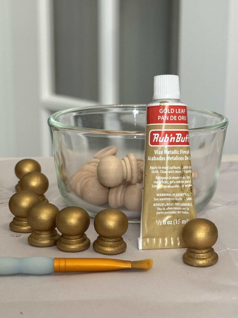 Step five to make a DIY Christmas Tree Collar is to paint small wood knobs gold with Rub-n-Buff. 