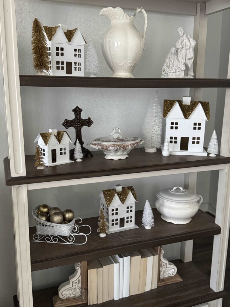 Shelves with white and gold Christmas village houses. 