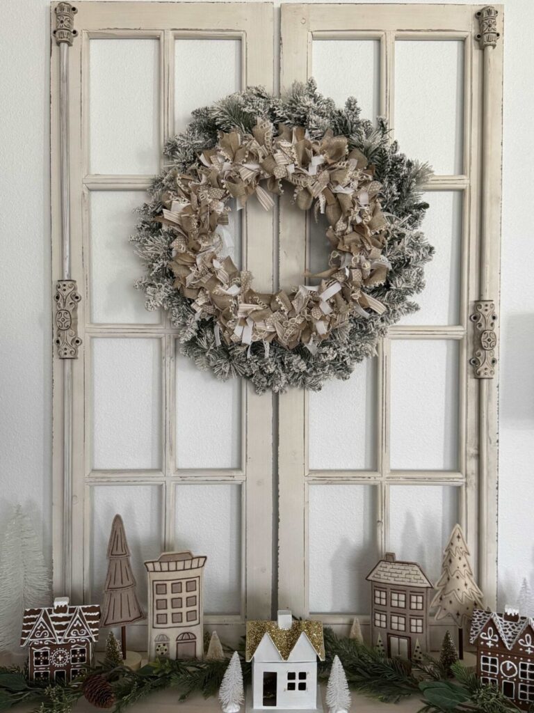 A neutral ribbon wreath layered over a flocked Christmas wreath. 