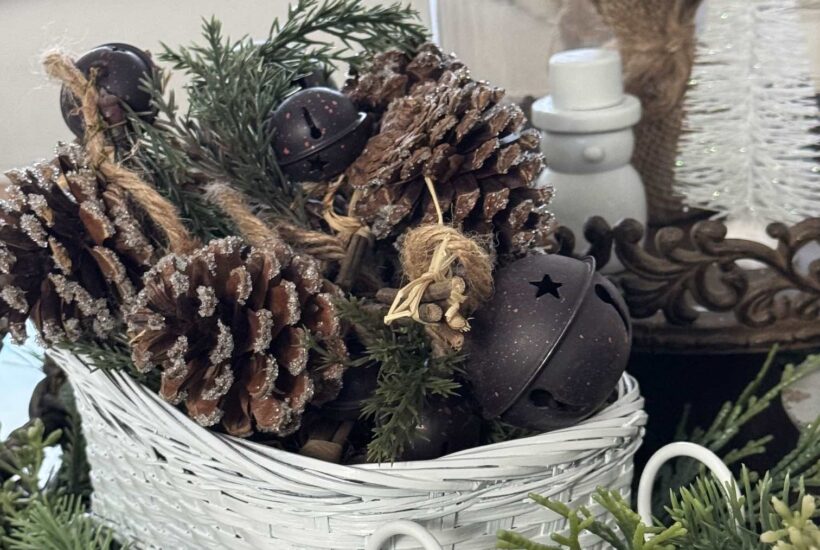 White wicker sled filled with pinecones, bells, and greenery.