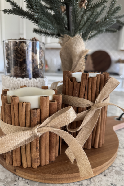 Two DIY cinnamon stick candles on a kitchen counter.