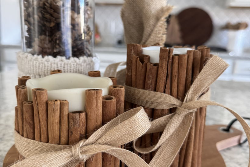 Two DIY cinnamon stick candles on a kitchen counter.