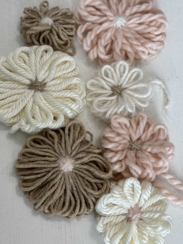 Neutral yarn flowers in taupe, cream. and pink. 