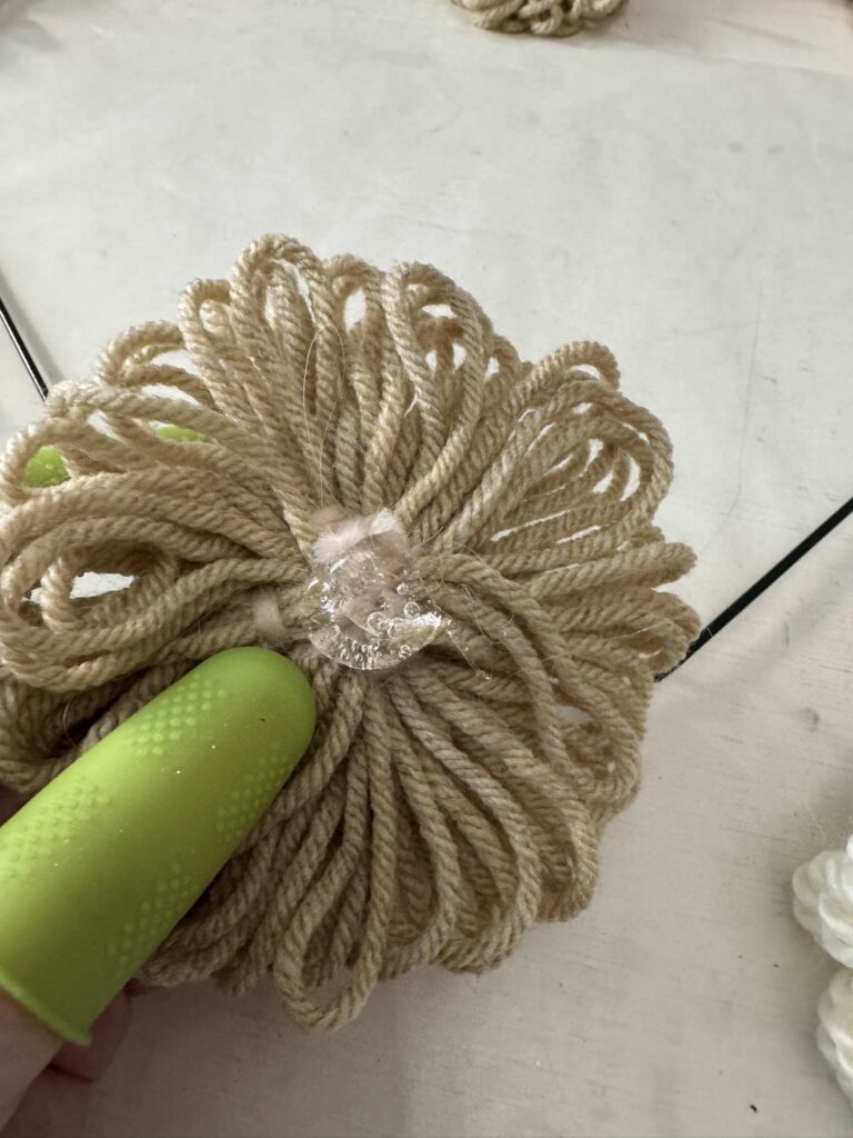 Someone holding a yarn flower with hot glue on the back. 