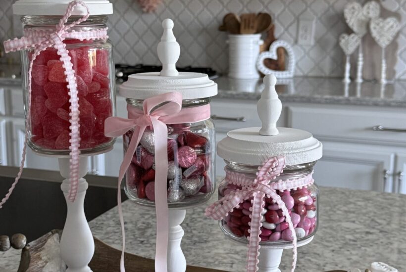 A set of three DIY candy jars filled with Valentine's sweets.