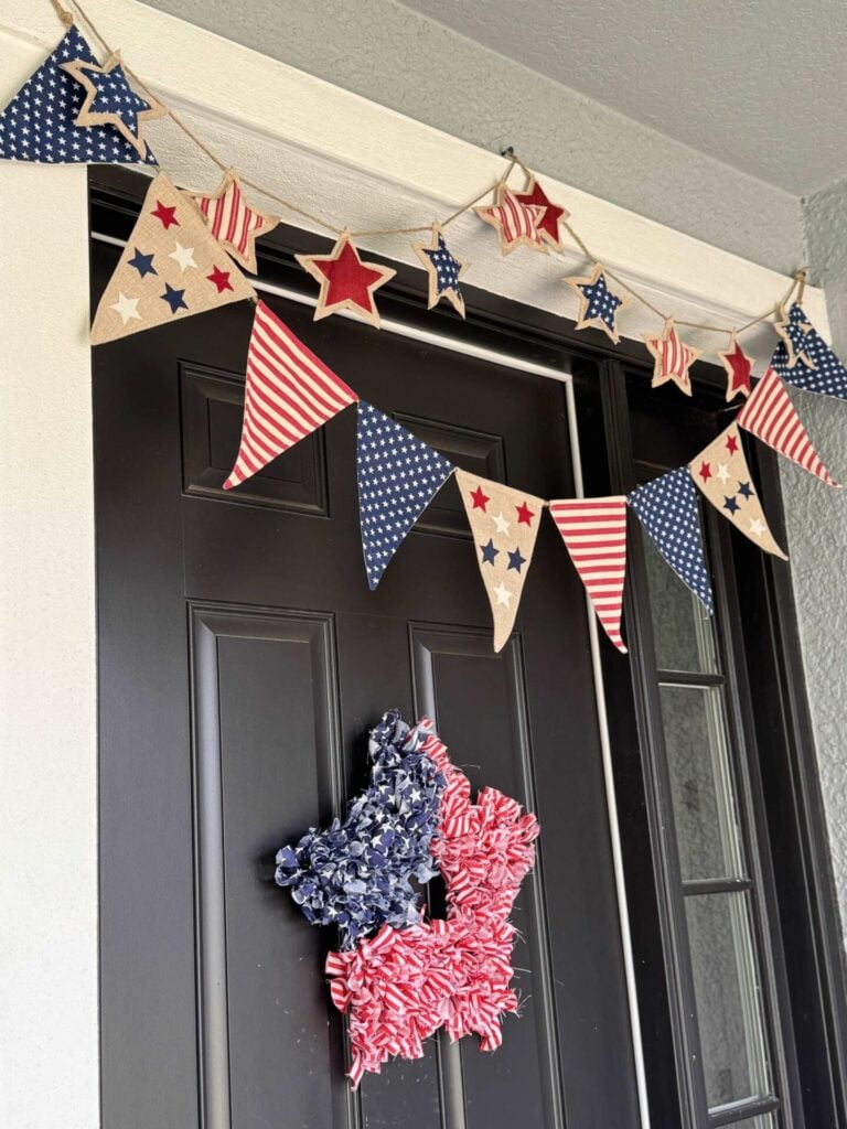 Two 4th of July garlands hanging over the door on a front porch.