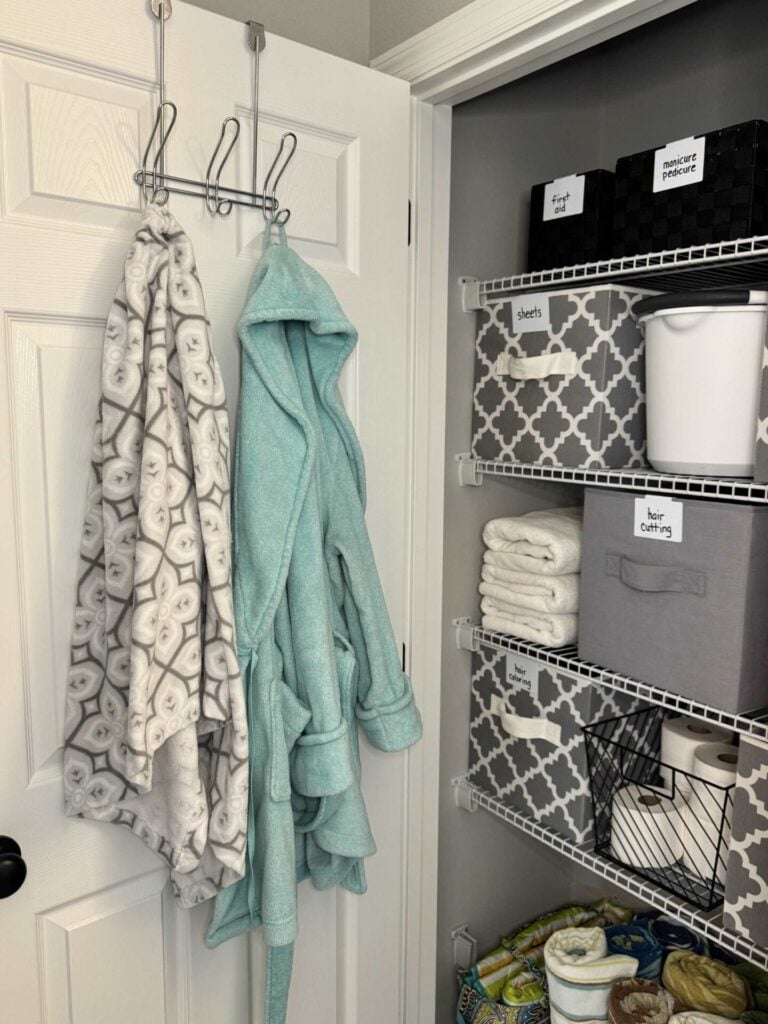 A robe and wrap towel hanging on the back of a bathroom closet door. 