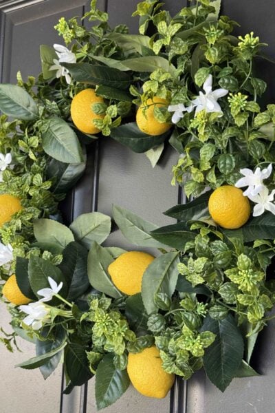 A DIY lemon wreath hanging on a black front door.