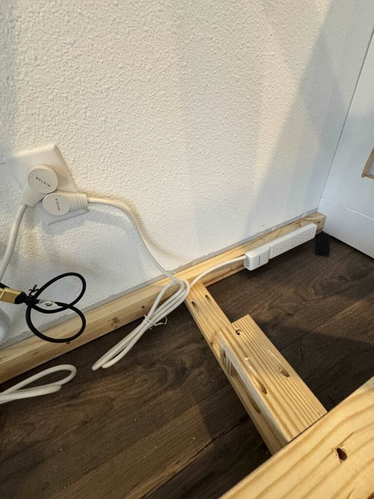two adjustable power strips plugged into wall plug and mounted on raw floor framing boards