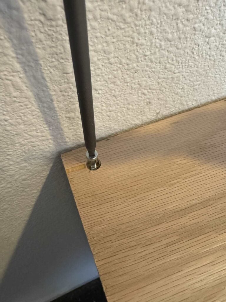 Pocket hole drill bit screwing in countersunk pocket hole screw into oak cabinet top