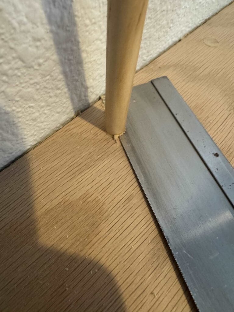 dowel inserted into countersunk screw hole being cut off flush to oak countertop by hand razor saw
