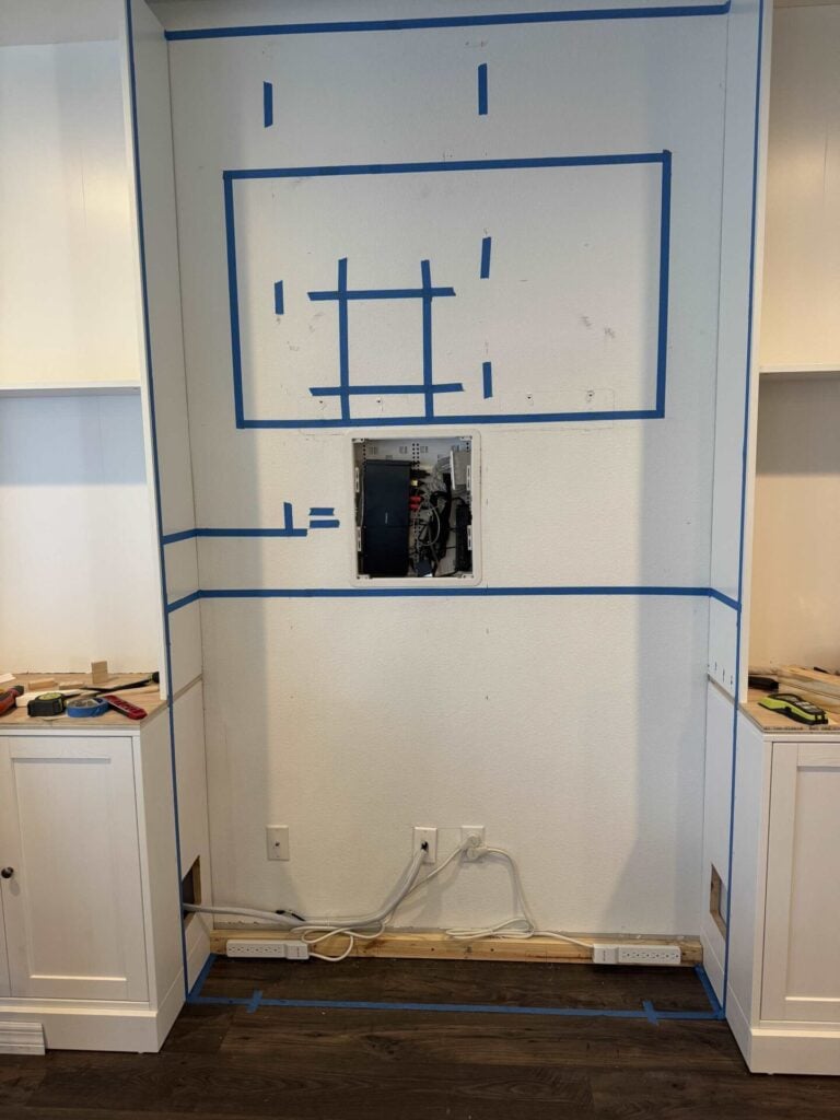 Original wall of house visible between cabinets and shelves marked with painters tape for tv wall design