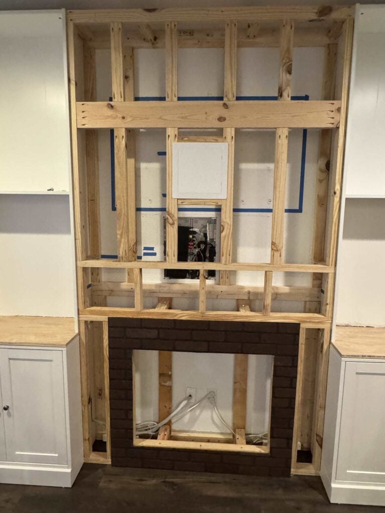 Final outside layer of tv wall framing above fireplace mantel to ceiling and showing plastic access panel