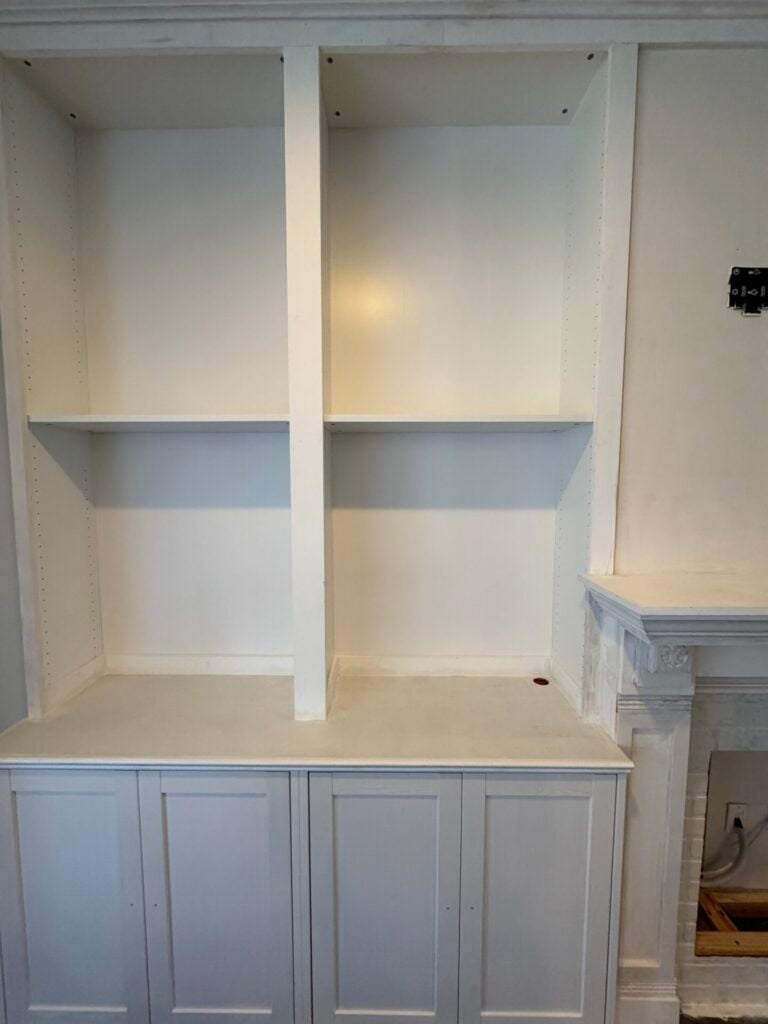 Left side of built in with two white cabinets and bookshelves. All is primed and painted. Part of mantle visible on the right