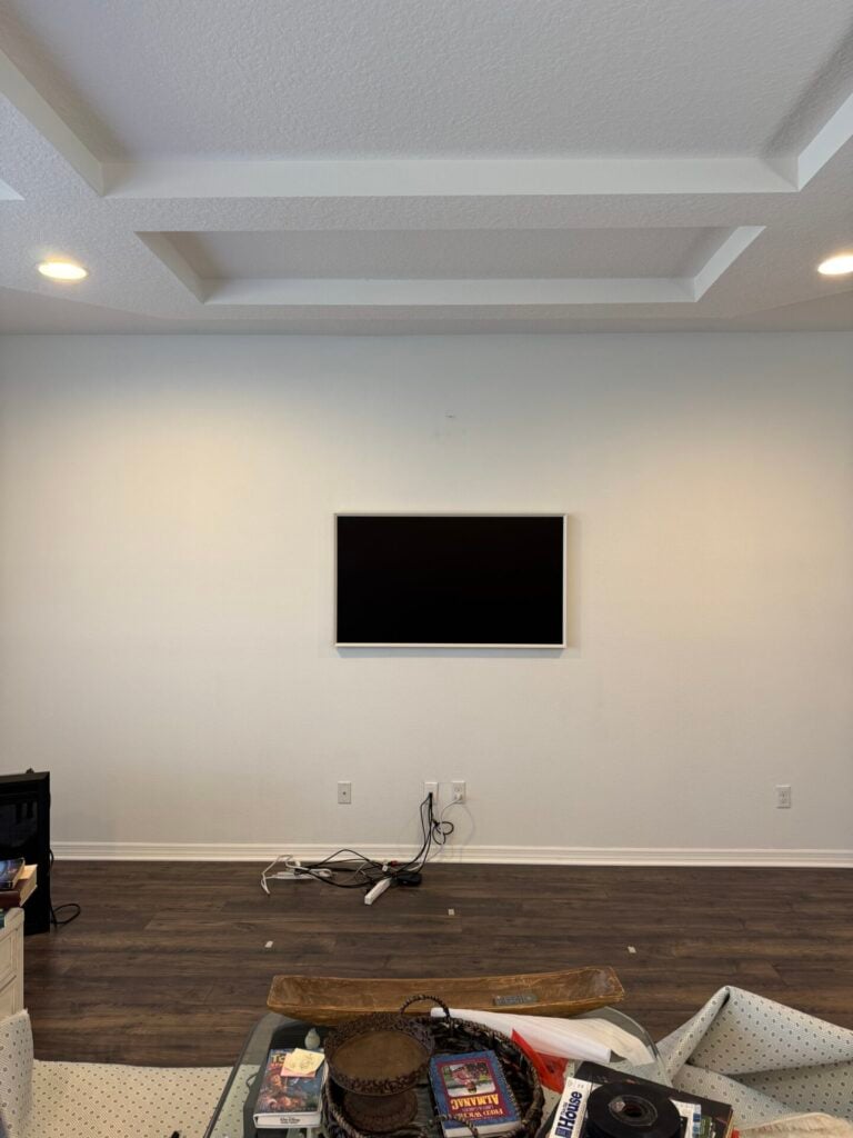 TV on a blank living room wall where they are planning an IKEA cabinet hack. 