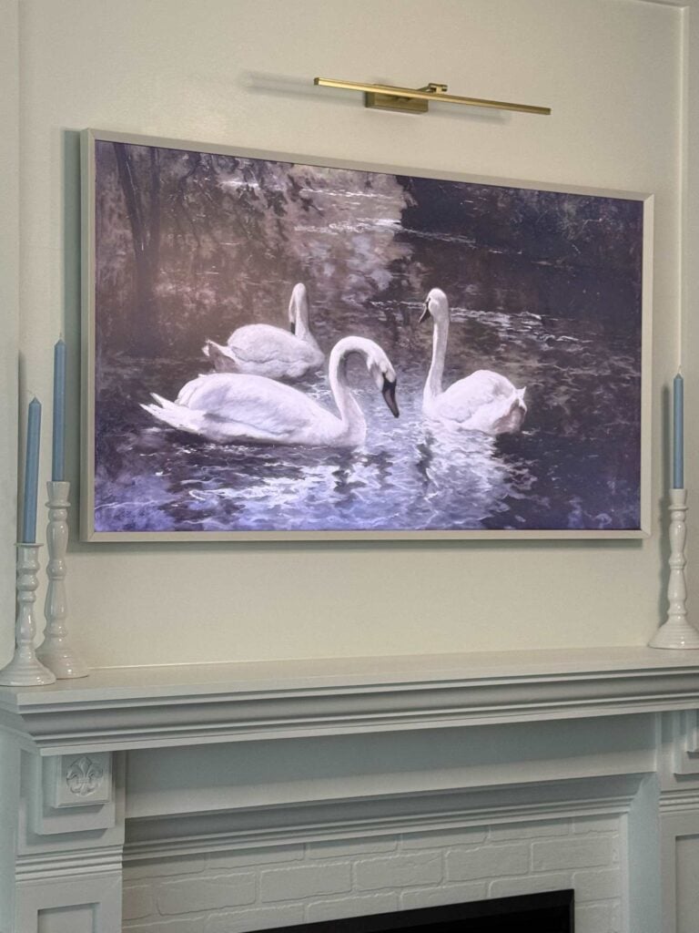 Gold light hanging over a picture frame TV. 