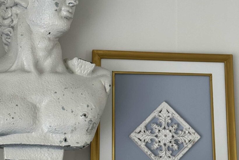 DIY framed art with wood emblem next to an antique bust.
