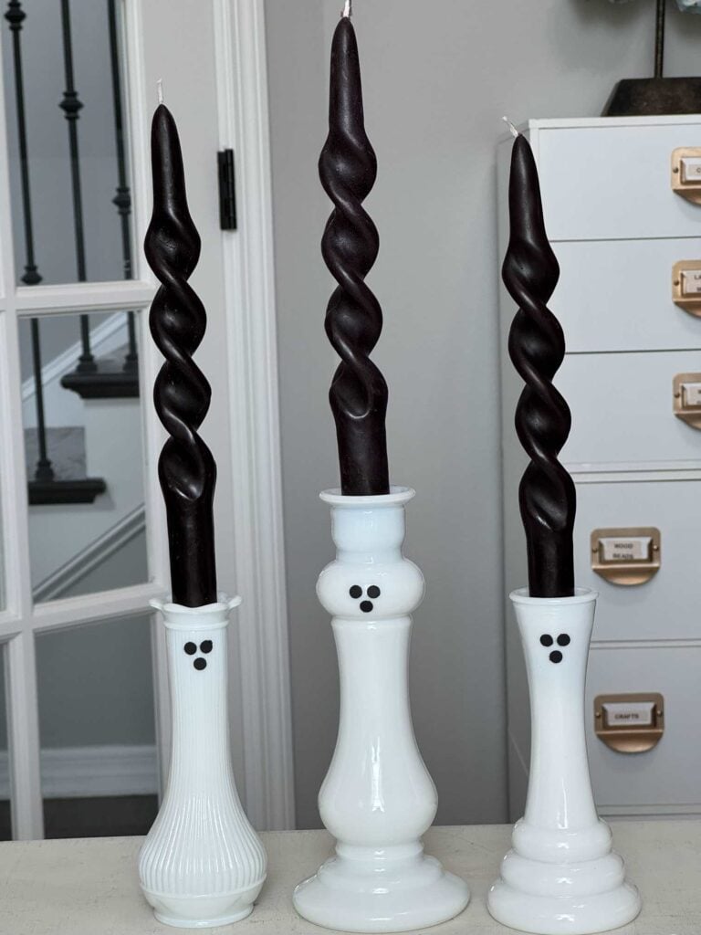 Three DIY milk glass ghost decor with twisted black candles.