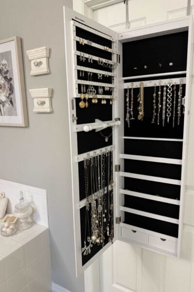 Over-the-door jewelry organizer with black velvet lining holding necklaces, bracelets, earrings, and rings.