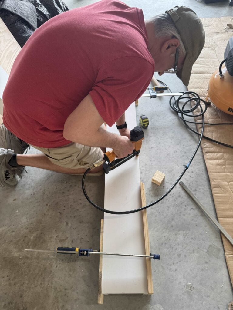 Man using brad nail gun to attach front board to column side boards and supports