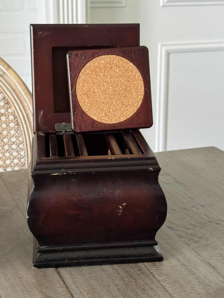 A dark decorative wood box with a set of coasters inside.