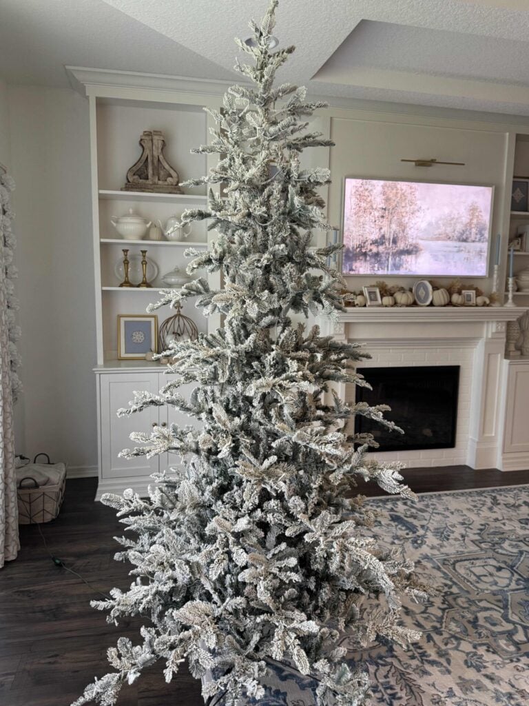 Faux flocked tree in a living room. Step two to decorate a Christmas tree: fluff the branches.