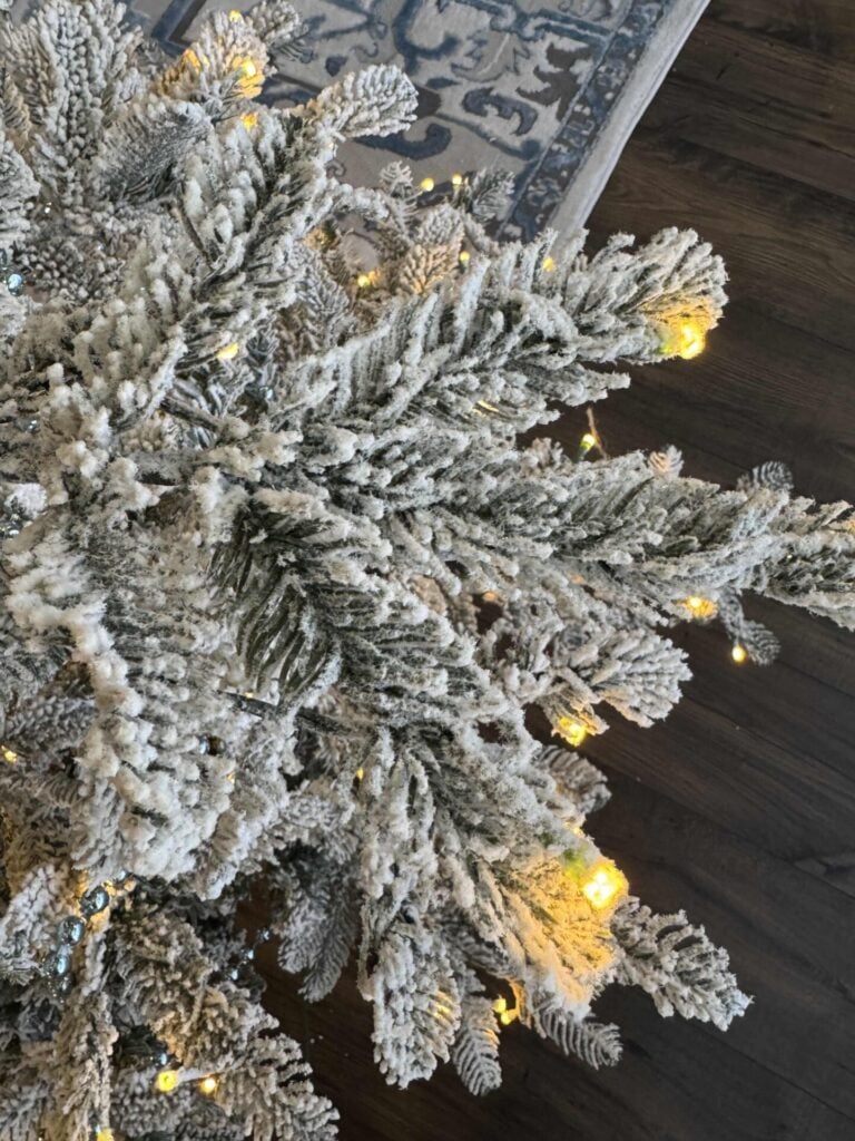 Step three to decorate a faux flocked Christmas tree: turn on pre lit lights or add lights if needed.