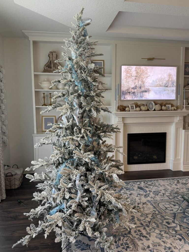 Step five to decorate a faux flocked Christmas tree: add pieces of twisted ribbon by tucking them in the branches.