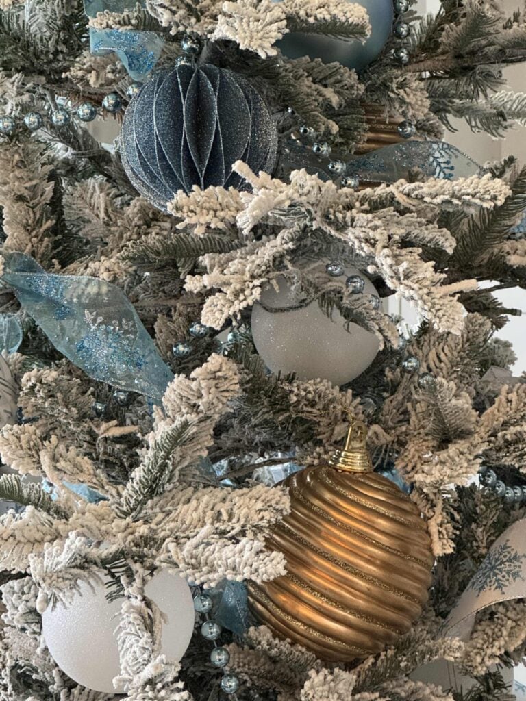 Step seven to decorate a faux flocked Christmas tree: is to hang the largest ornaments in the interior of the tree close to the trunk.