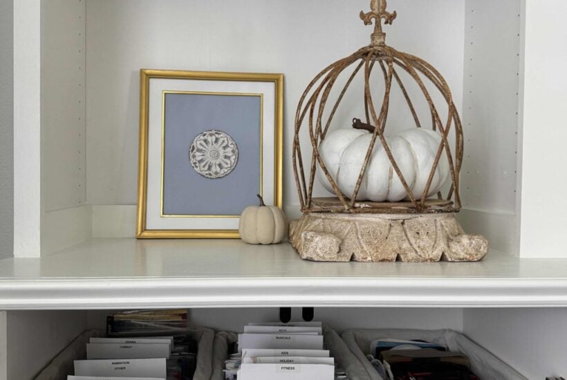 Living room cabinet with DVDS organized in gray baskets.
