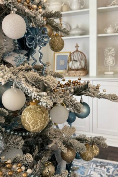 A flocked tree with blue, gold, and white ornaments.
