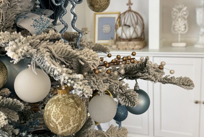 A flocked tree with blue, gold, and white ornaments.