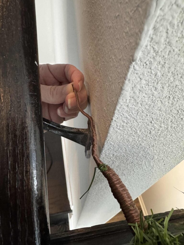 Someone holding the end of a Christmas garland over the railing they will hang it on. 