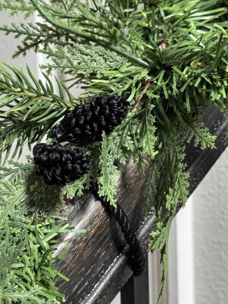 A black twist tie holding garland on a stair rail. 